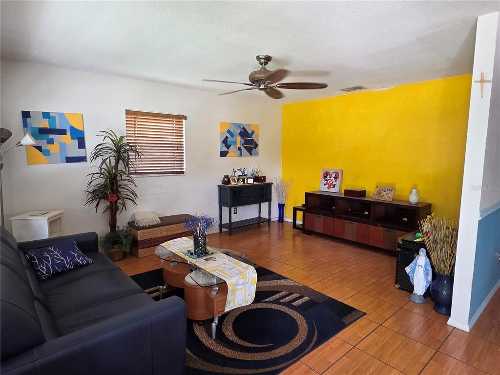 A living room features tile flooring, a yellow accent wall, and a dark sofa — 9272 51ST STREET N, PINELLAS PARK, FL