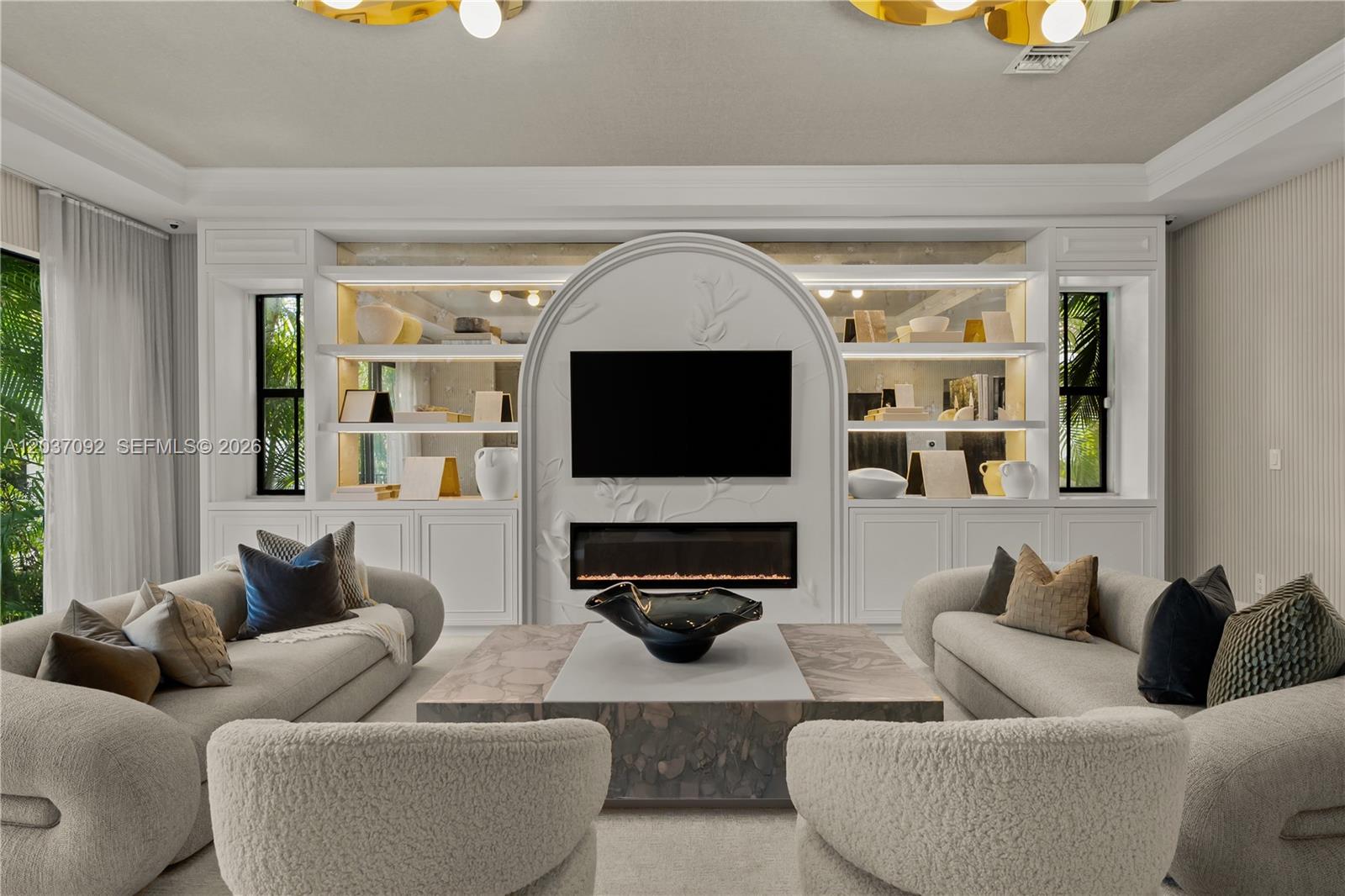 A living room features a central fireplace, a mounted television, and built-in shelving units — 1803 S Bayshore Ln, Miami FL 33133, MIAMI, FL