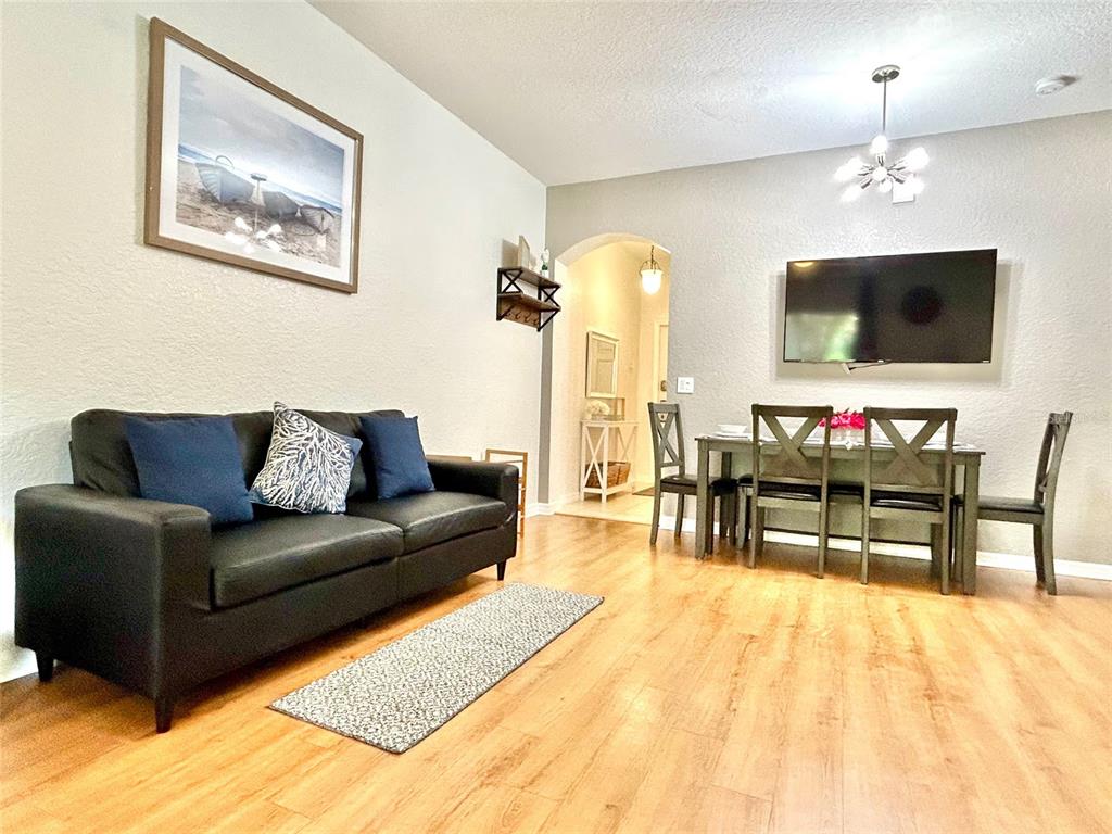 A living and dining room area features a black sofa, wooden floors, and a wall-mounted television — 616 VERONA AVE, DAVENPORT, FL