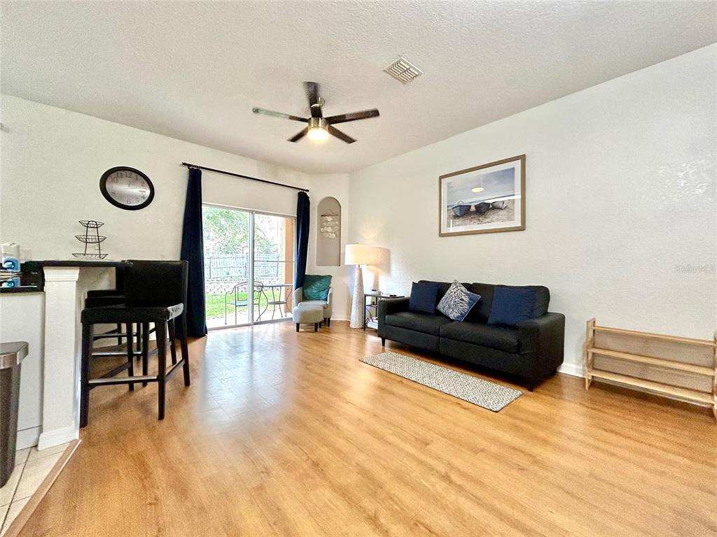 A living room features wood-look flooring, a black sofa, a ceiling fan, and sliding glass doors — 616 VERONA AVE, DAVENPORT, FL