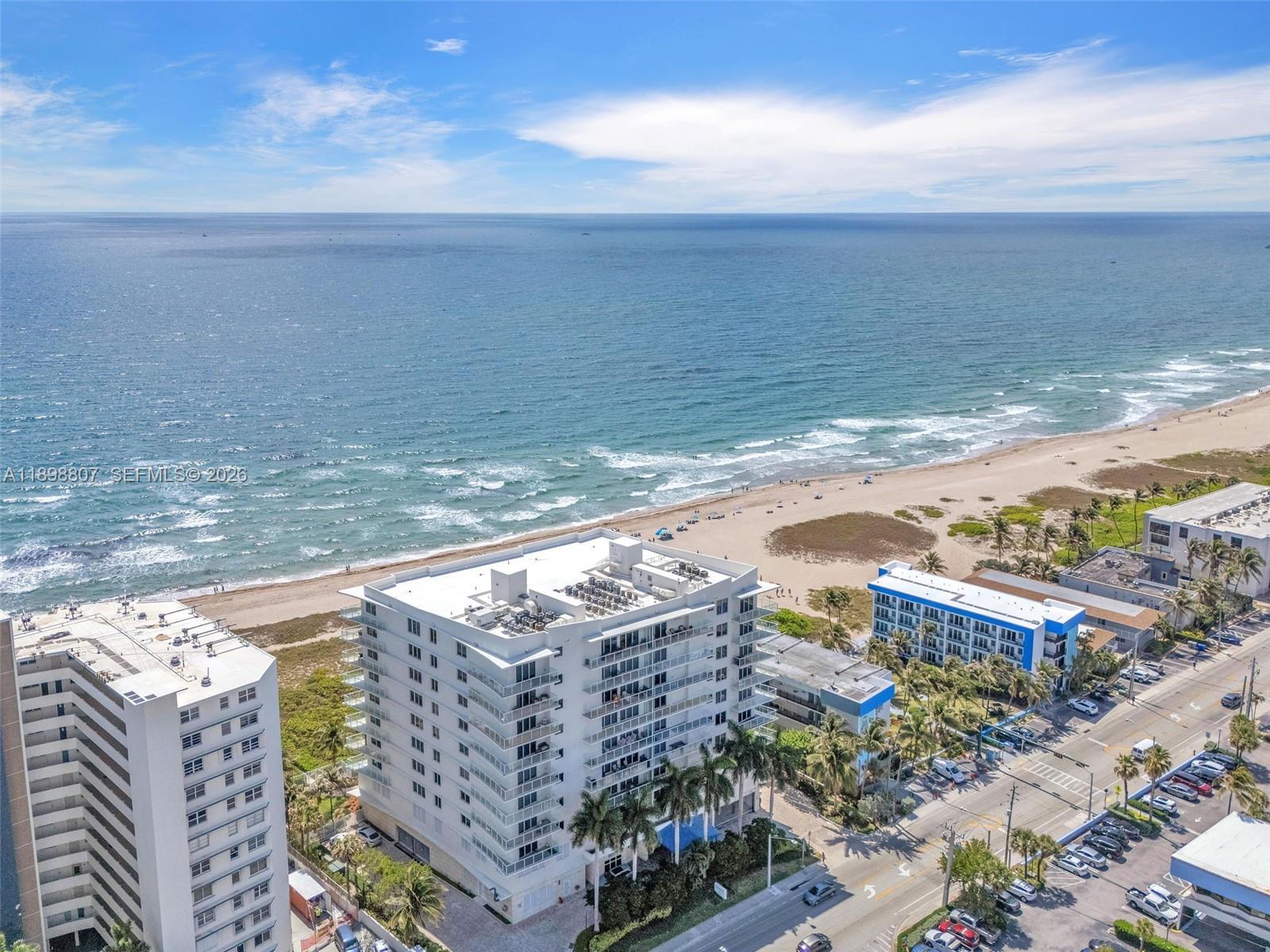 An aerial view shows beachfront apartment buildings, a sandy beach, and the ocean — 704 N Ocean Blvd # 804, Pompano Beach FL 33062, POMPANO BEACH, FL