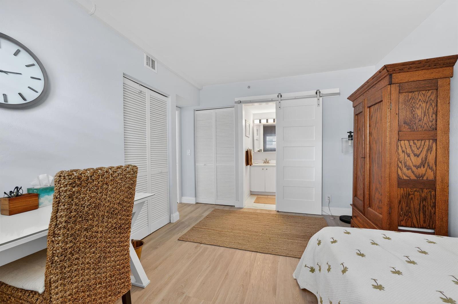 A bedroom features light wood flooring, a barn door to a bathroom, and wooden furniture — 3101 S Ocean Boulevard # 302, Highland Beach FL 33487, HIGHLAND BEACH, FL