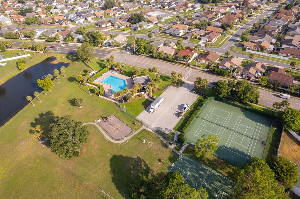 An aerial view shows a community park with a swimming pool, tennis courts, and playground — 4783 WARRIOR LANE, KISSIMMEE, FL