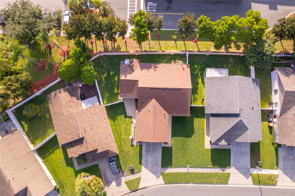 An aerial view shows three suburban houses with brown roofs and driveways in a neighborhood — 4783 WARRIOR LANE, KISSIMMEE, FL