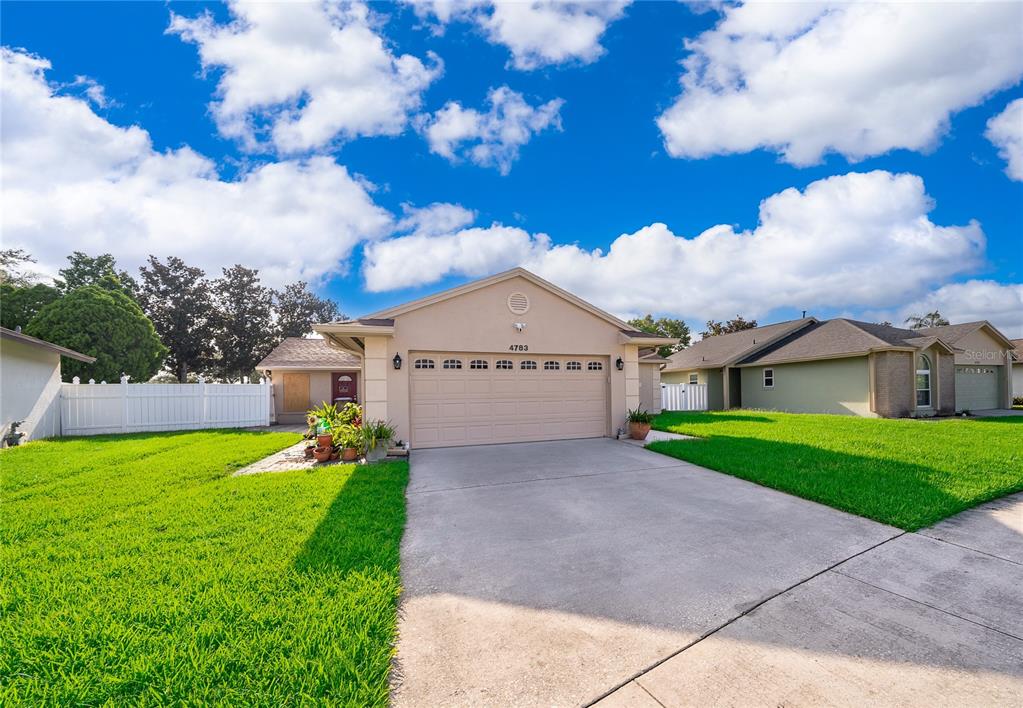 A single-story house with a beige exterior, a two-car garage, and a concrete driveway — 4783 WARRIOR LANE, KISSIMMEE, FL