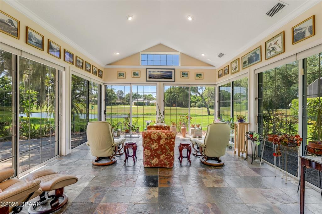 A sunroom with slate tile flooring, vaulted ceilings, and large glass walls overlooking a pond — 203 PRESTWICK DRIVE, NEW SMYRNA BEACH, FL