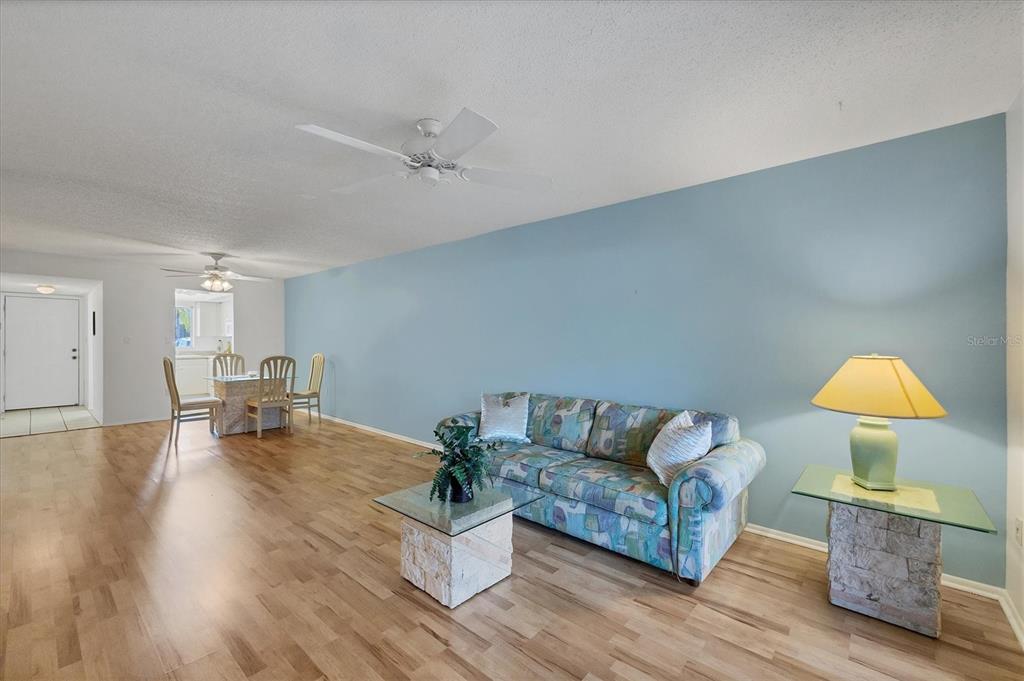 A living room features a patterned sofa, glass-topped tables, and light wood flooring — 3534 LAKE BAYSHORE DRIVE UNIT K118, BRADENTON, FL