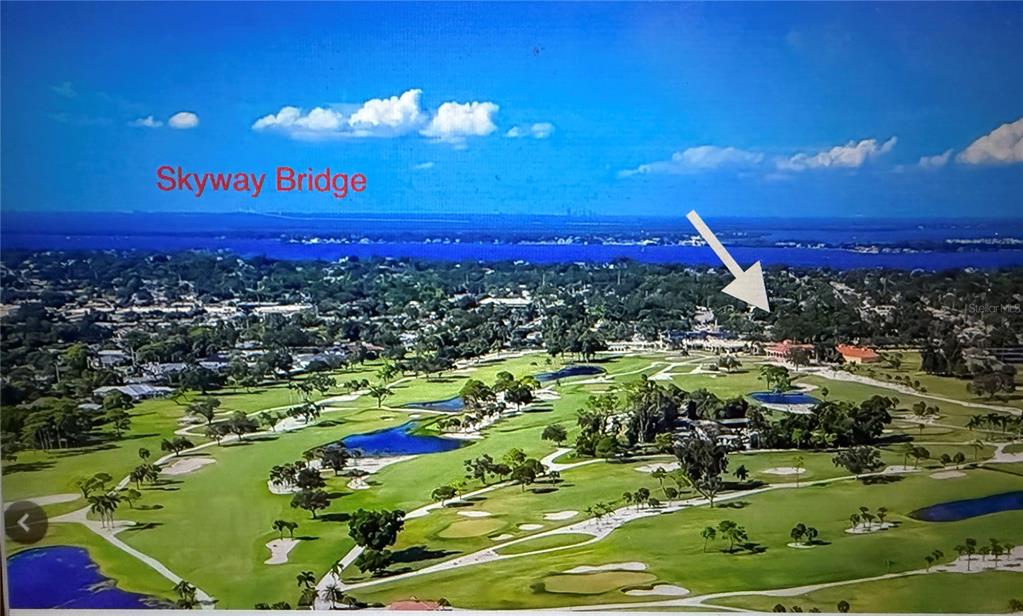 An aerial view of a golf course with a distant bridge and a white arrow — 4620 7TH AVENUE W, BRADENTON, FL