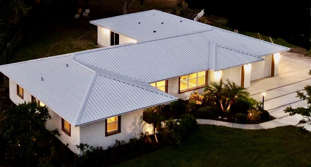 An aerial view of a single-story house with a white metal roof and landscaped yard — 4620 7TH AVENUE W, BRADENTON, FL