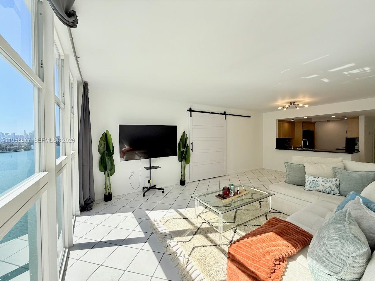 A bright living room features white tile floors, a glass coffee table, and a water view — 1228 West Ave # 1415, Miami Beach FL 33139, MIAMI BEACH, FL
