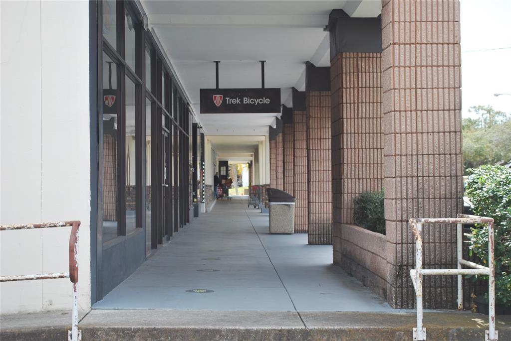 A covered outdoor walkway leads past a Trek Bicycle store with brick support columns — 3185 4TH STREET N, ST PETERSBURG, FL