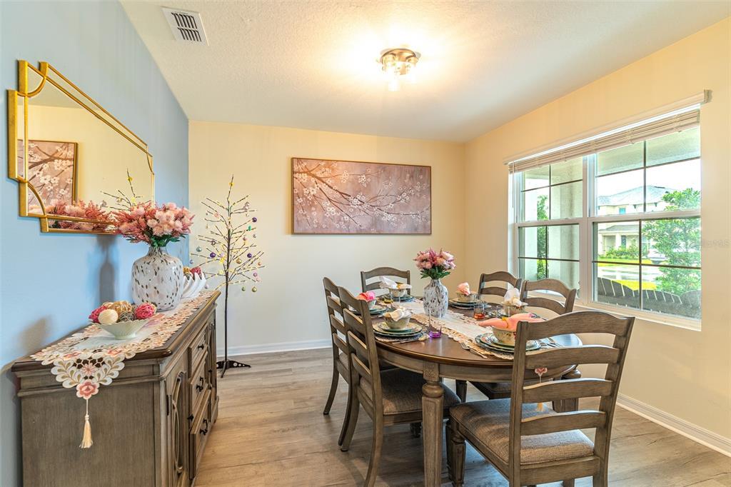 A dining room features a wooden table, chairs, a sideboard, and a large window — 1328 DAISY FIELD DRIVE, WINTER HAVEN, FL