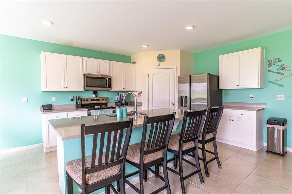 A kitchen with white cabinets, a large island with seating, and light green walls — 1328 DAISY FIELD DRIVE, WINTER HAVEN, FL
