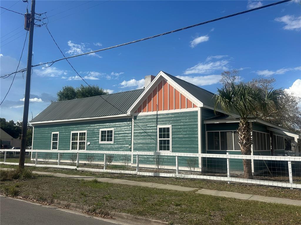 A green, single-story house with a metal roof and a white fence sits outdoors — 503 N POLK AVENUE, ARCADIA, FL