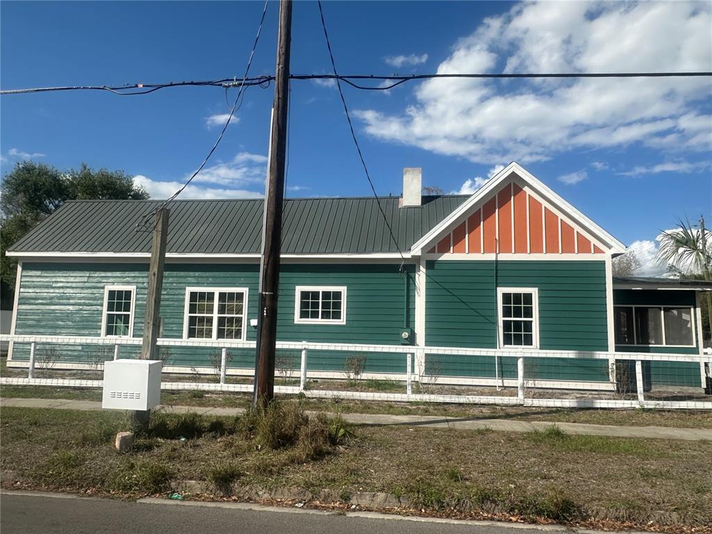 A green, single-story house with a metal roof and white trim sits behind a fence — 503 N POLK AVENUE, ARCADIA, FL