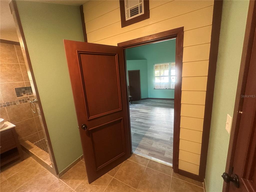 A view from a tiled bathroom through an open door into a wood-floored room — 503 N POLK AVENUE, ARCADIA, FL