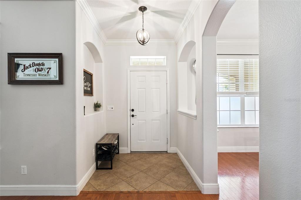 An entryway features a white front door, tile flooring, a shoe rack, and arched alcoves — 30148 JUTLAND COURT, MOUNT DORA, FL