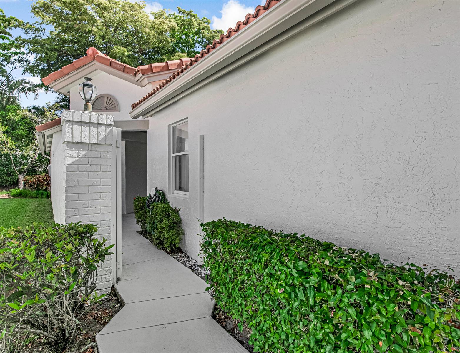 A concrete walkway leads to a side entrance along a white stucco exterior wall — 9758 Harbour Lake Circle, Boynton Beach FL 33437, BOYNTON BEACH, FL