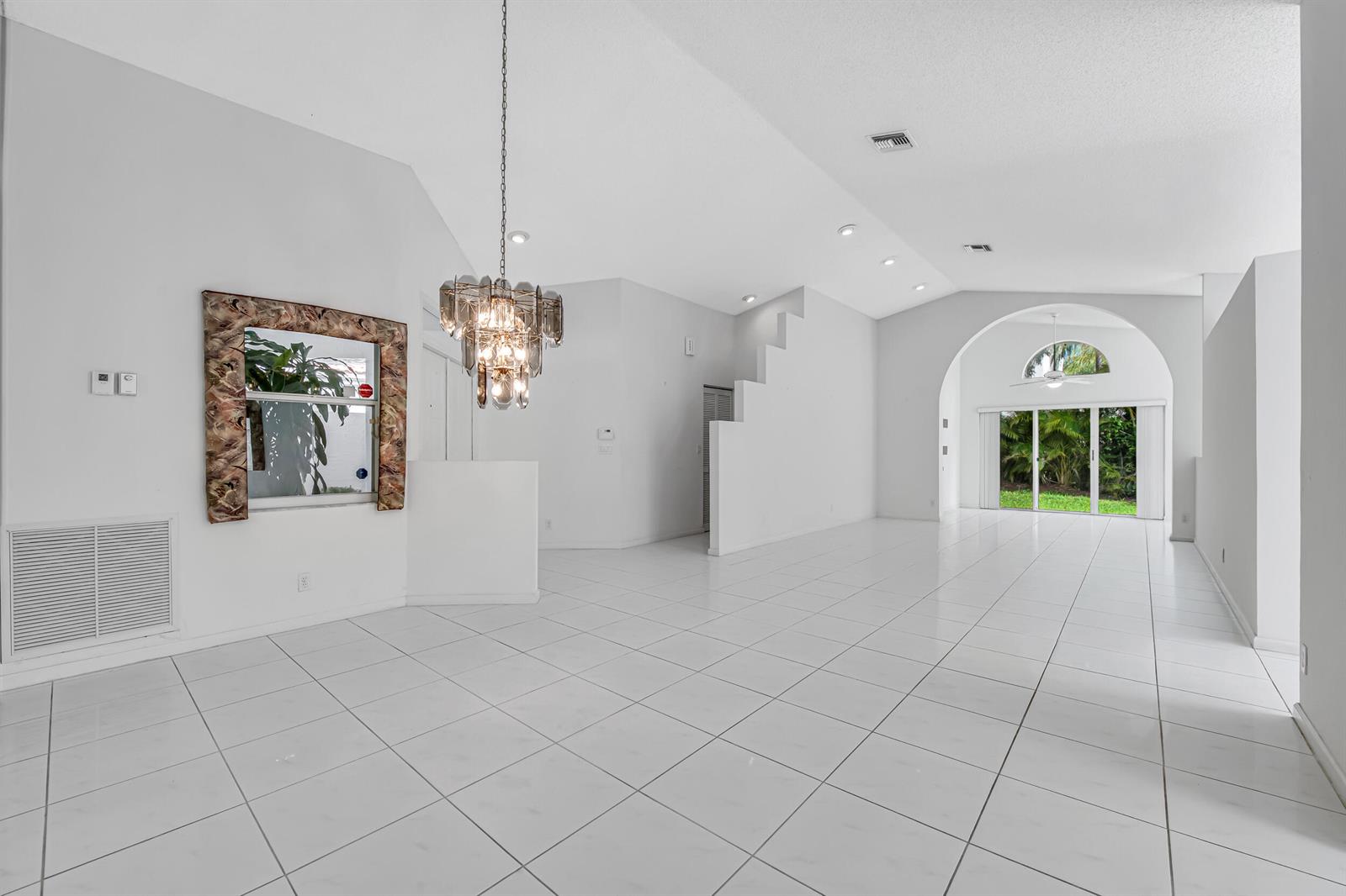 A bright, open-concept living area features white tile floors, a vaulted ceiling, and a chandelier — 9758 Harbour Lake Circle, Boynton Beach FL 33437, BOYNTON BEACH, FL