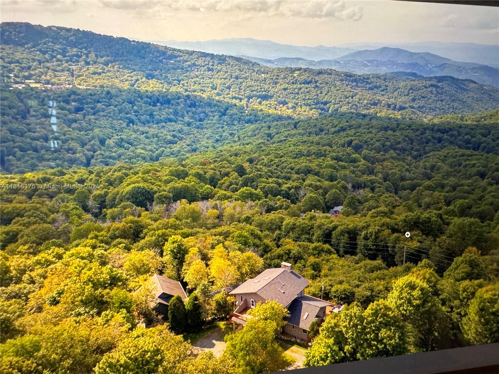 An aerial view shows a house nestled in a dense, forested mountain landscape — 200 Summit Lodge Road, NC 28604, NC