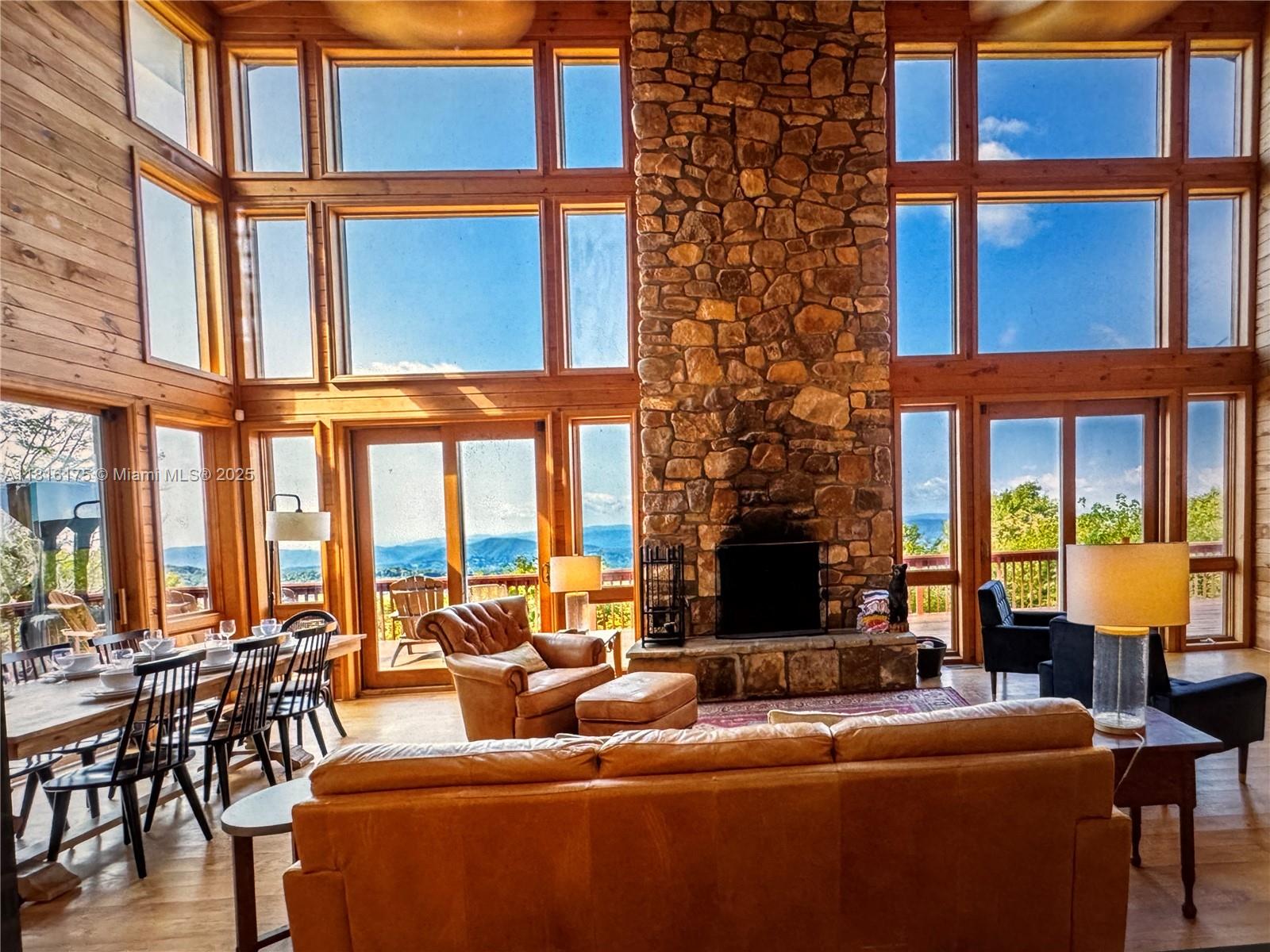 A rustic living room features a stone fireplace, floor-to-ceiling windows, and mountain views — 200 Summit Lodge Road, NC 28604, NC