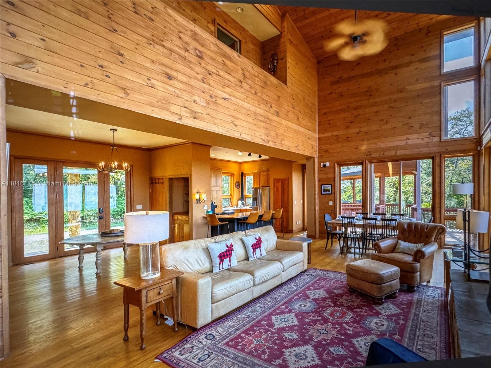 A spacious living room with wood-paneled walls, vaulted ceilings, a leather sofa, and dining area — 200 Summit Lodge Road, NC 28604, NC