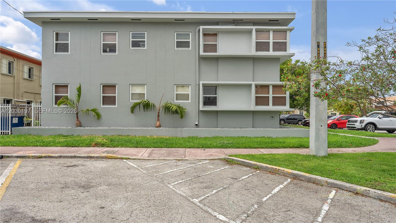 A two-story gray apartment building features rectangular windows and a paved parking lot in front — 1905 Calais Dr # 6, Miami Beach FL 33141, MIAMI BEACH, FL
