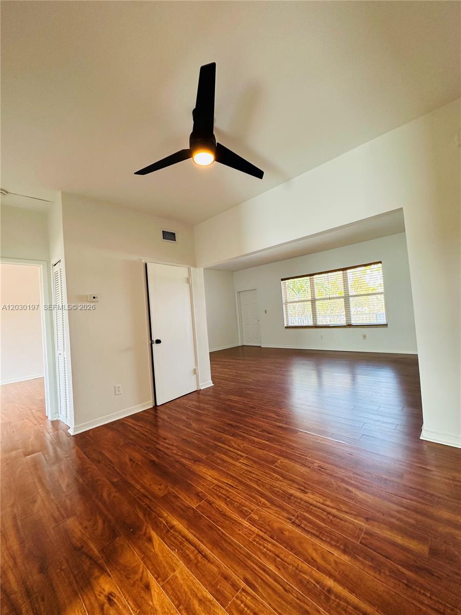 An empty room features wood-look flooring, a modern ceiling fan, and white walls — 1905 Calais Dr # 6, Miami Beach FL 33141, MIAMI BEACH, FL
