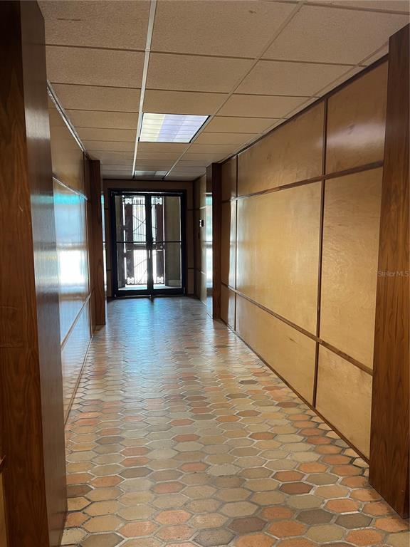 A hallway with wood-paneled walls, a drop ceiling, and a hexagonal tile floor — 204 W UNIVERSITY AVENUE UNIT 8A, GAINESVILLE, FL