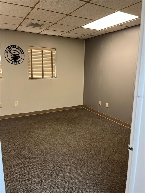 An empty office room features beige and gray paneled walls, brown carpeting, and a drop ceiling — 204 W UNIVERSITY AVENUE UNIT 8A, GAINESVILLE, FL