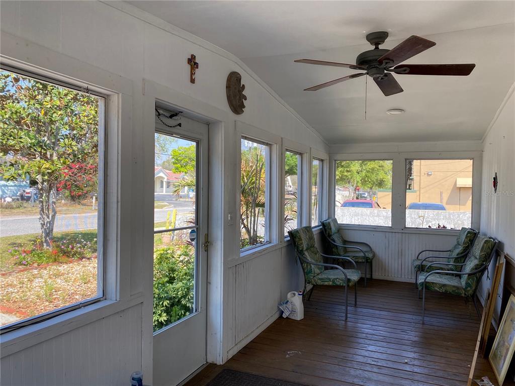 A sunroom features a wooden floor, a ceiling fan, multiple windows, and patio furniture — 313 S OBSERVATORY DRIVE, ORLANDO, FL
