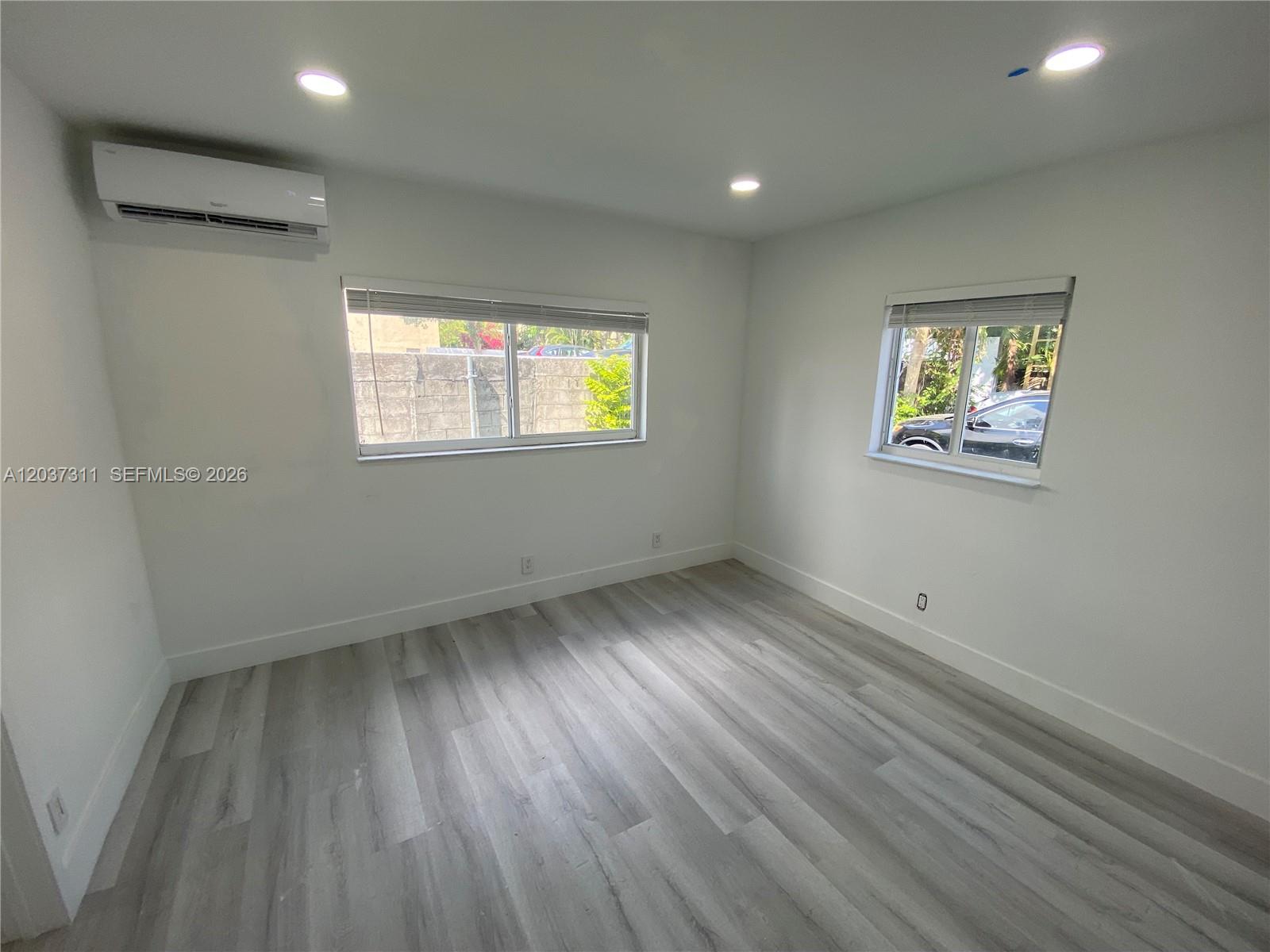 An empty bedroom features white walls, light wood-look flooring, recessed lighting, and a wall-mounted air conditioner — 3071 SW 27th Ave # 4, Miami FL 33133, MIAMI, FL