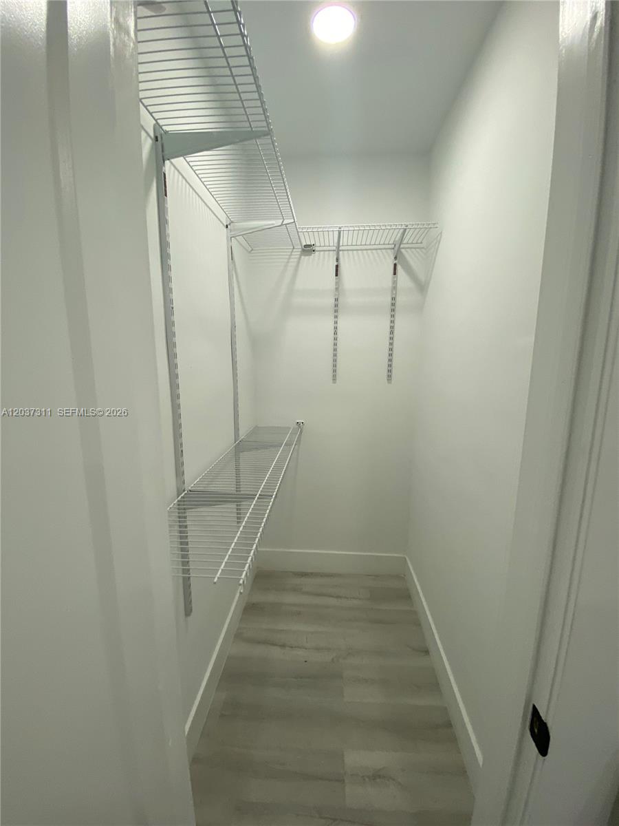A small walk-in closet features white walls, light wood-look flooring, and wire shelving — 3071 SW 27th Ave # 4, Miami FL 33133, MIAMI, FL