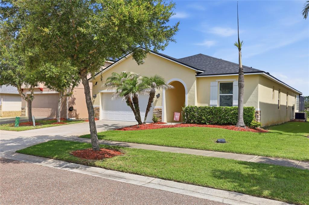 A single-story yellow house with a two-car garage and a front lawn under a blue sky — 4733 BLUE DIAMOND STREET, KISSIMMEE, FL