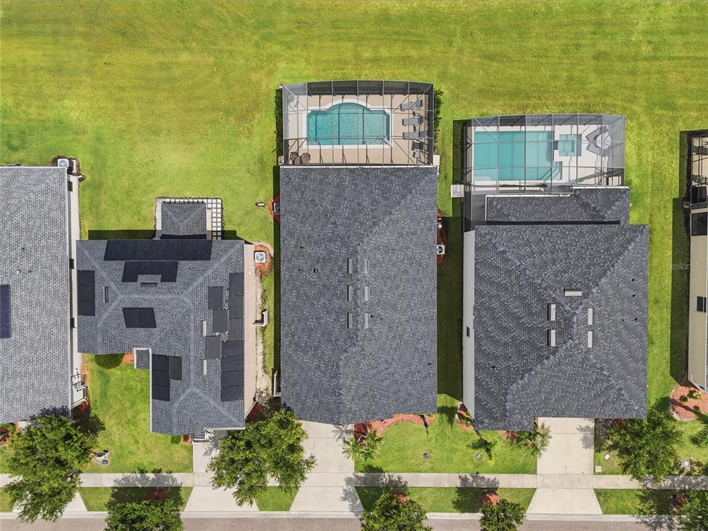 An aerial view shows three houses with swimming pools and screened lanais in a suburban neighborhood — 4733 BLUE DIAMOND STREET, KISSIMMEE, FL
