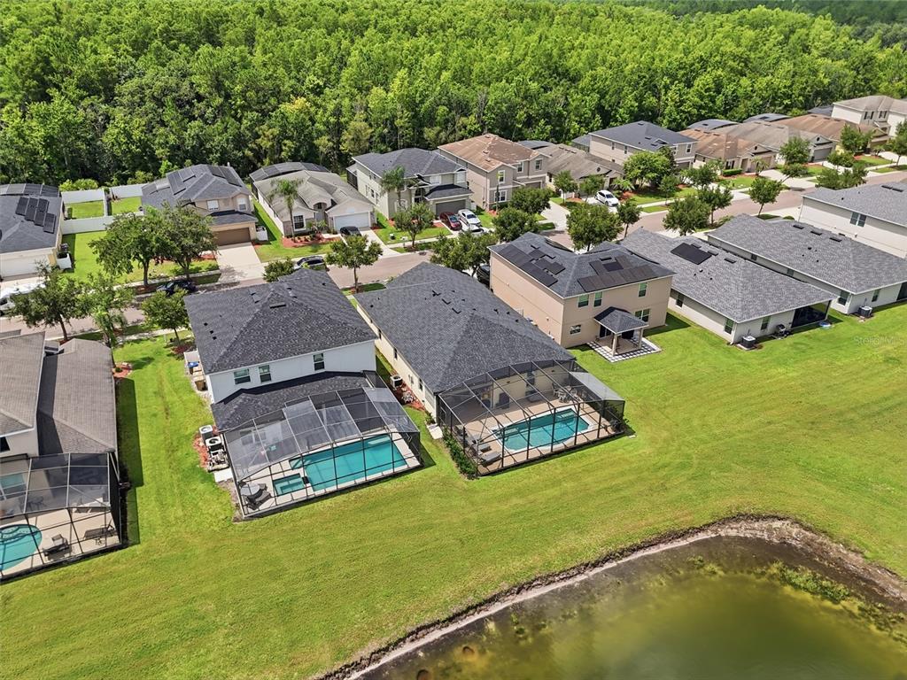 An aerial view shows several suburban houses with screened-in pools backing onto a pond — 4733 BLUE DIAMOND STREET, KISSIMMEE, FL