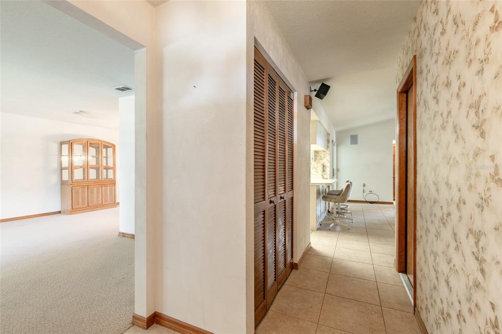 A hallway with tiled flooring and louvered closet doors leads toward a kitchen and living area — 4576 PHIPPS DRIVE, PORT ORANGE, FL