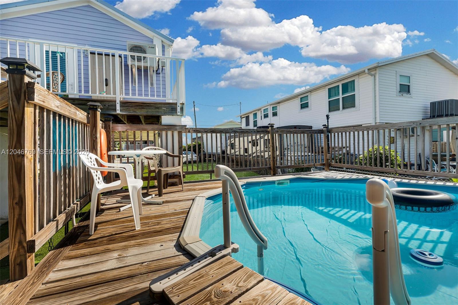 An elevated wooden deck features a swimming pool, patio furniture, and a safety railing — 925 83rd Street Ocean, Marathon FL 33050, MARATHON, FL