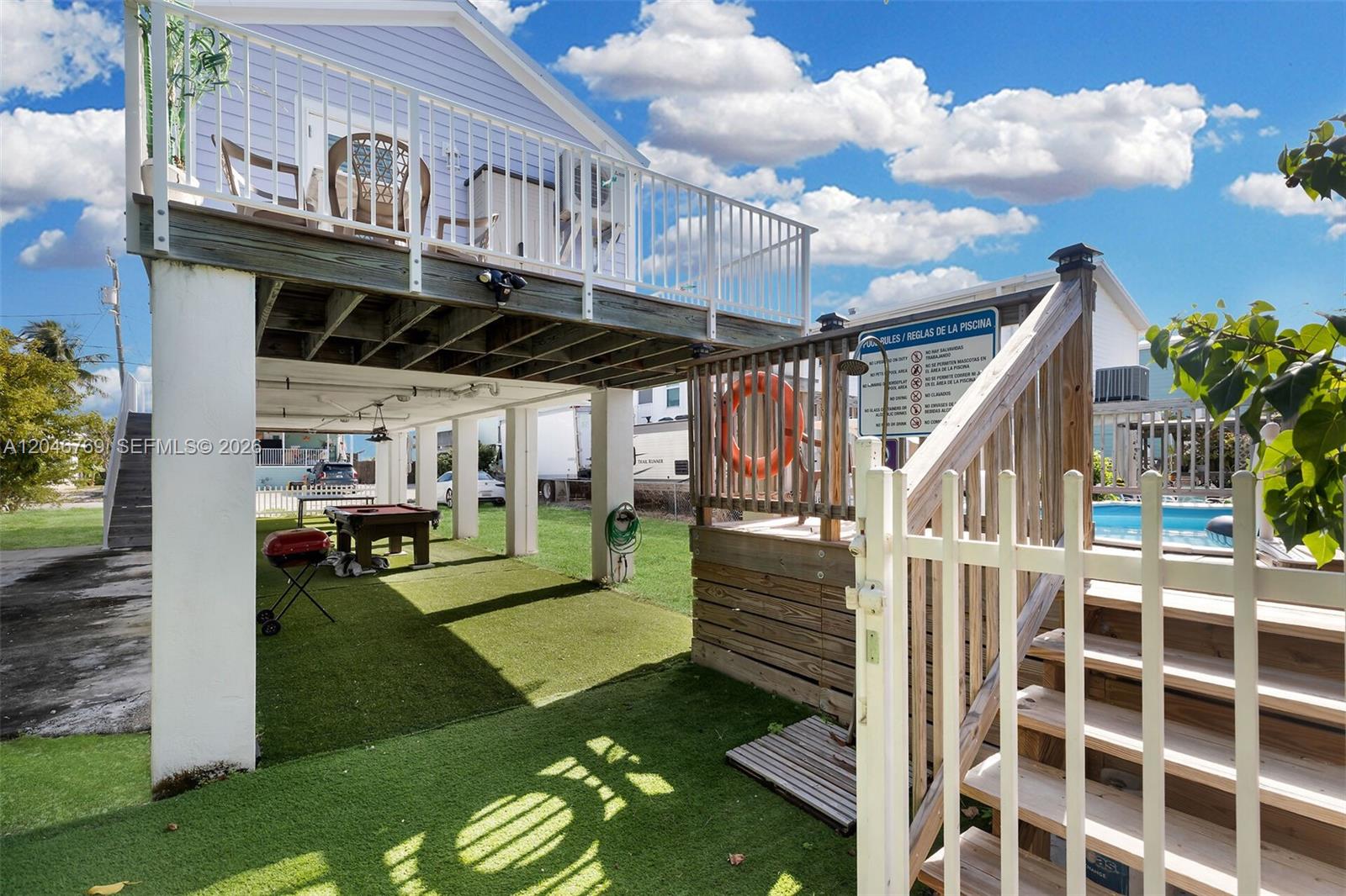An elevated house features a covered patio area with a pool table and artificial turf — 925 83rd Street Ocean, Marathon FL 33050, MARATHON, FL