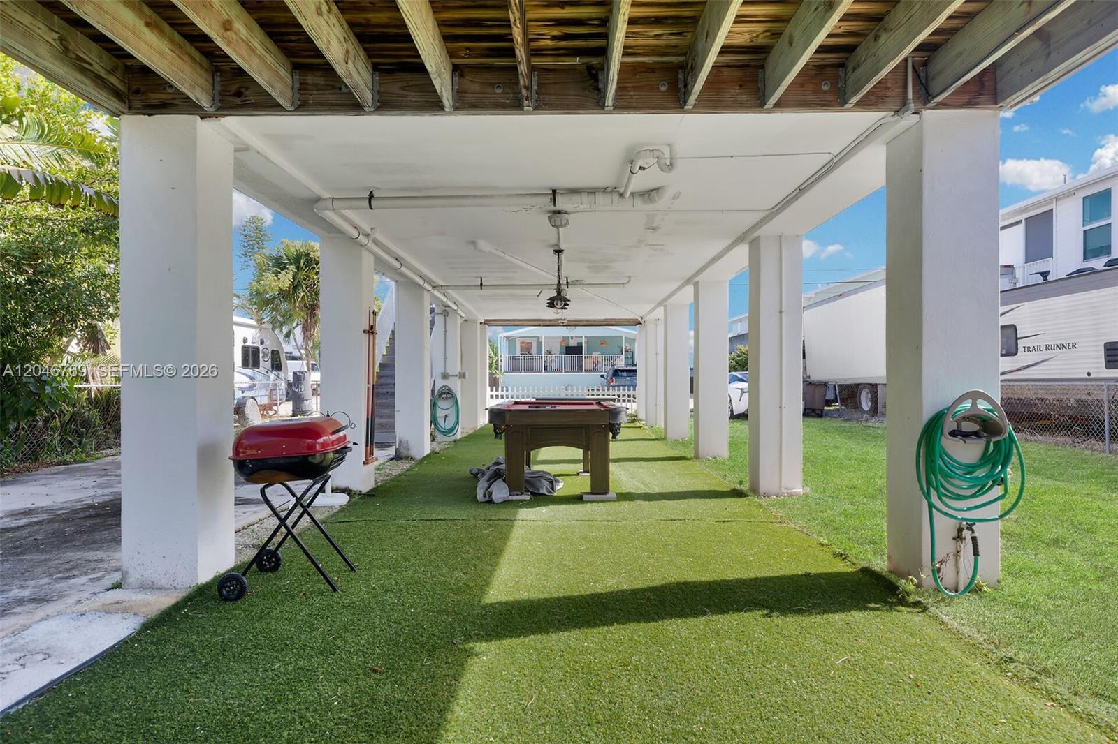 A covered outdoor patio features a pool table, artificial turf, and a charcoal grill — 925 83rd Street Ocean, Marathon FL 33050, MARATHON, FL
