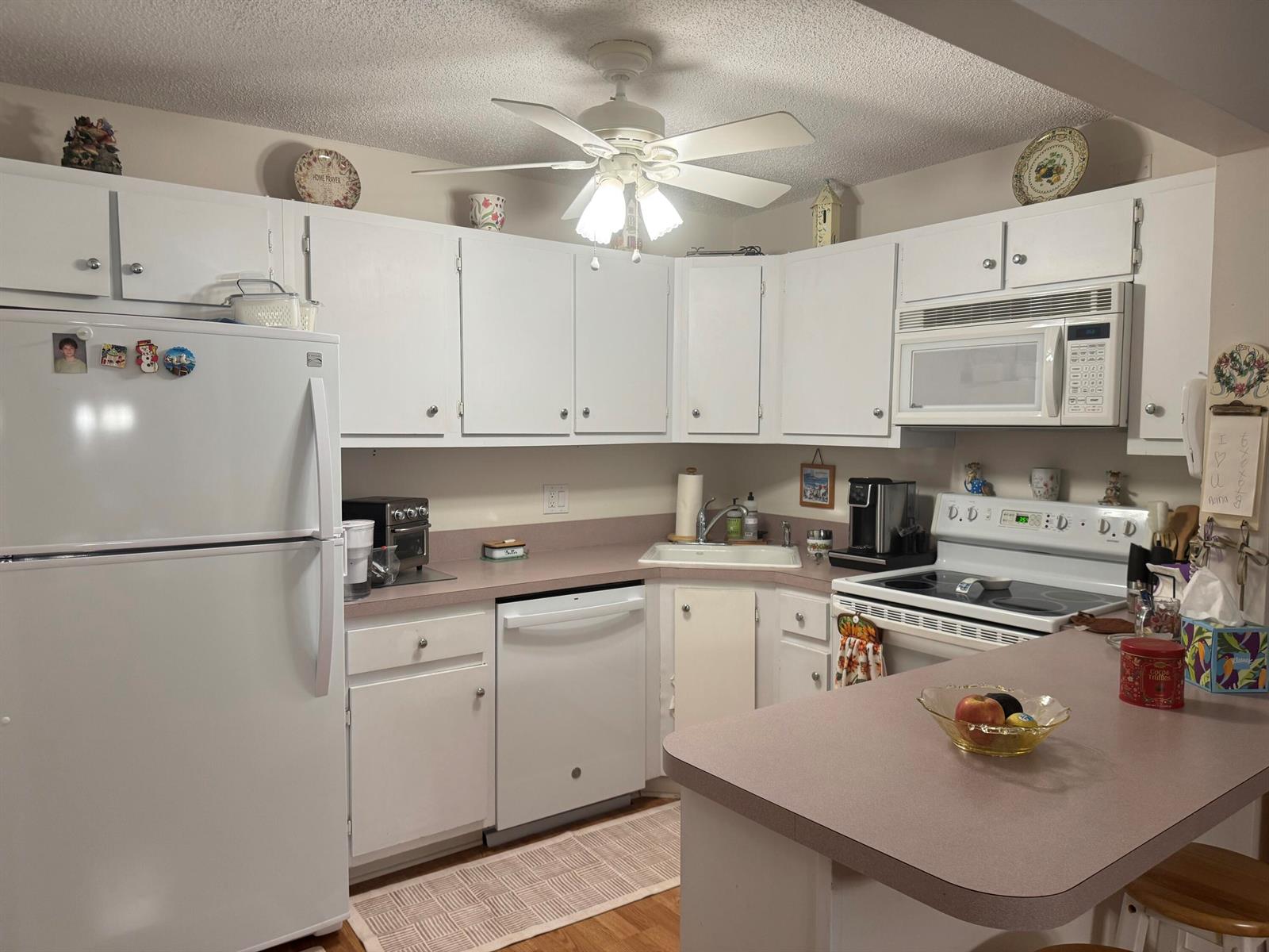 A kitchen with white cabinets, laminate countertops, a white refrigerator, and a ceiling fan — 417 Pine Glen Lane # 2, FL 33463, FL
