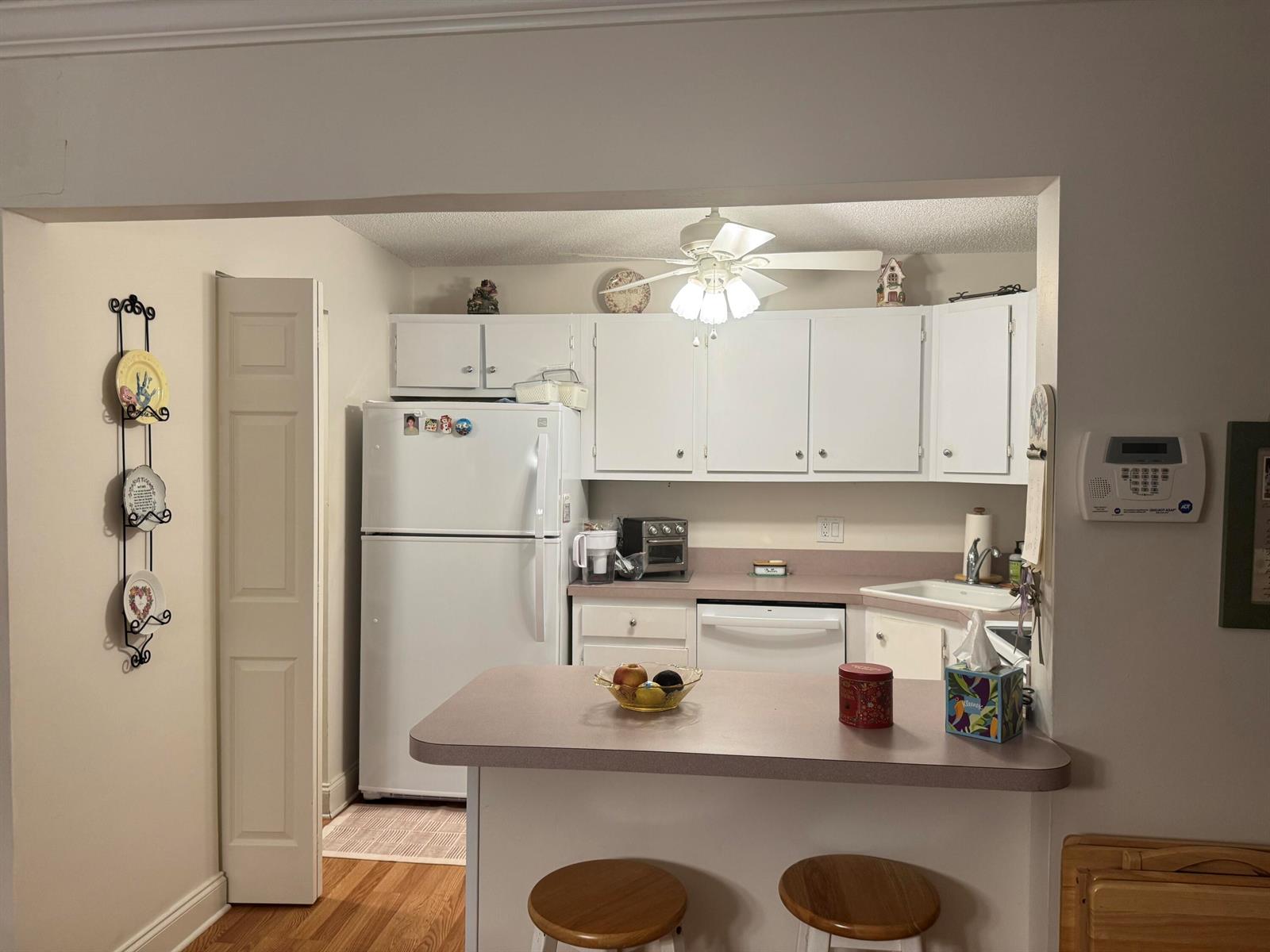 A kitchen features white cabinets, a white refrigerator, a breakfast bar, and a ceiling fan — 417 Pine Glen Lane # 2, FL 33463, FL