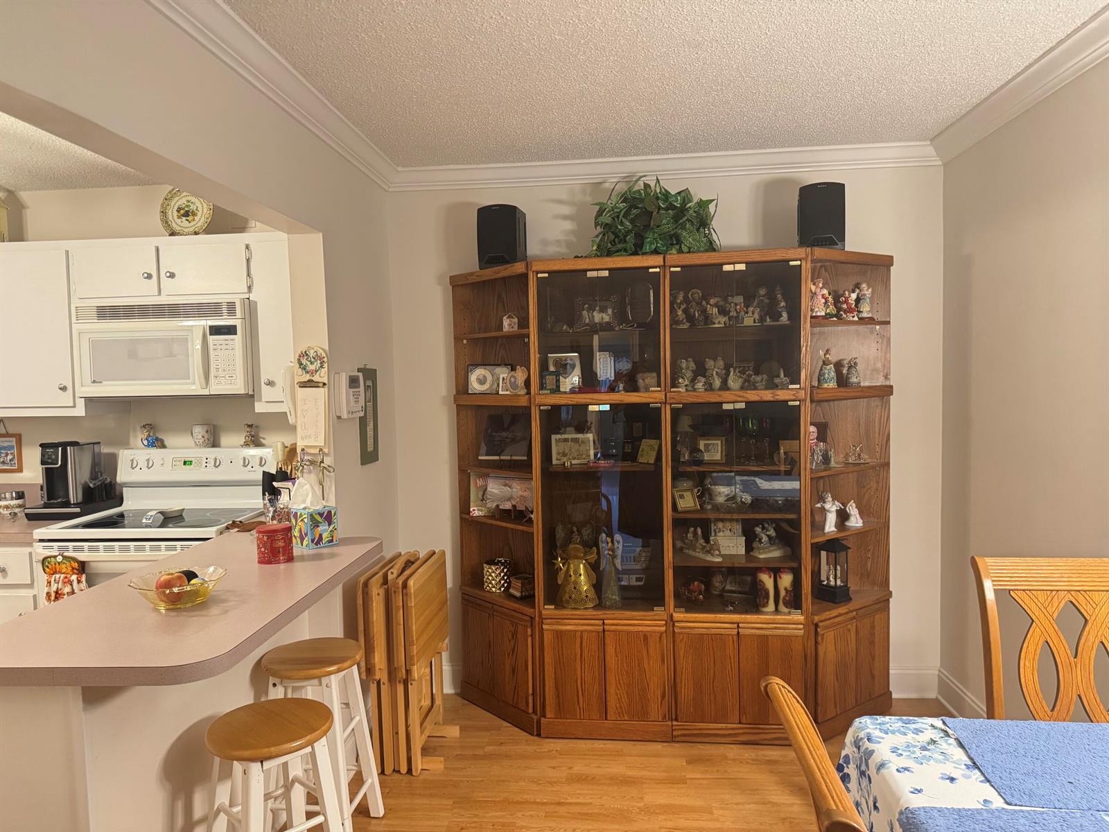A kitchen with a breakfast bar, wooden display cabinet, and light-colored cabinetry — 417 Pine Glen Lane # 2, FL 33463, FL