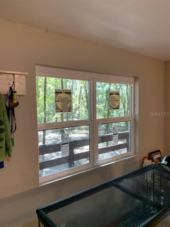A room features a double-hung window overlooking a wooded area and a wooden deck railing — 4919 NE 18 TRAIL, TRENTON, FL