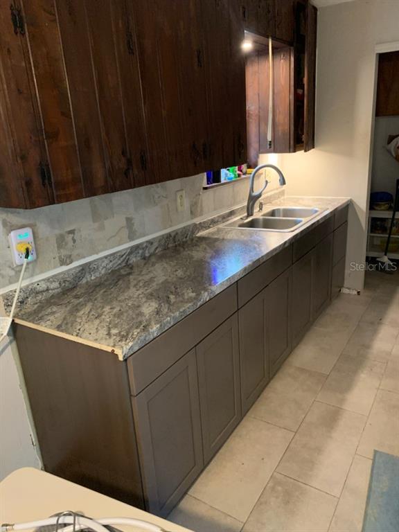 A kitchen features dark wood upper cabinets, gray lower cabinets, and a granite countertop — 4919 NE 18 TRAIL, TRENTON, FL