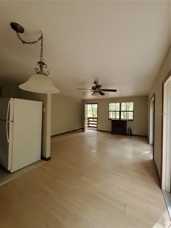 A living room with light wood flooring, a ceiling fan, and a white refrigerator — 4919 NE 18 TRAIL, TRENTON, FL