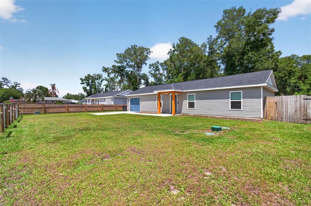 A gray-sided house with a blue garage door sits on a large, grassy lot — 14027 SE 43RD TERRACE, SUMMERFIELD, FL