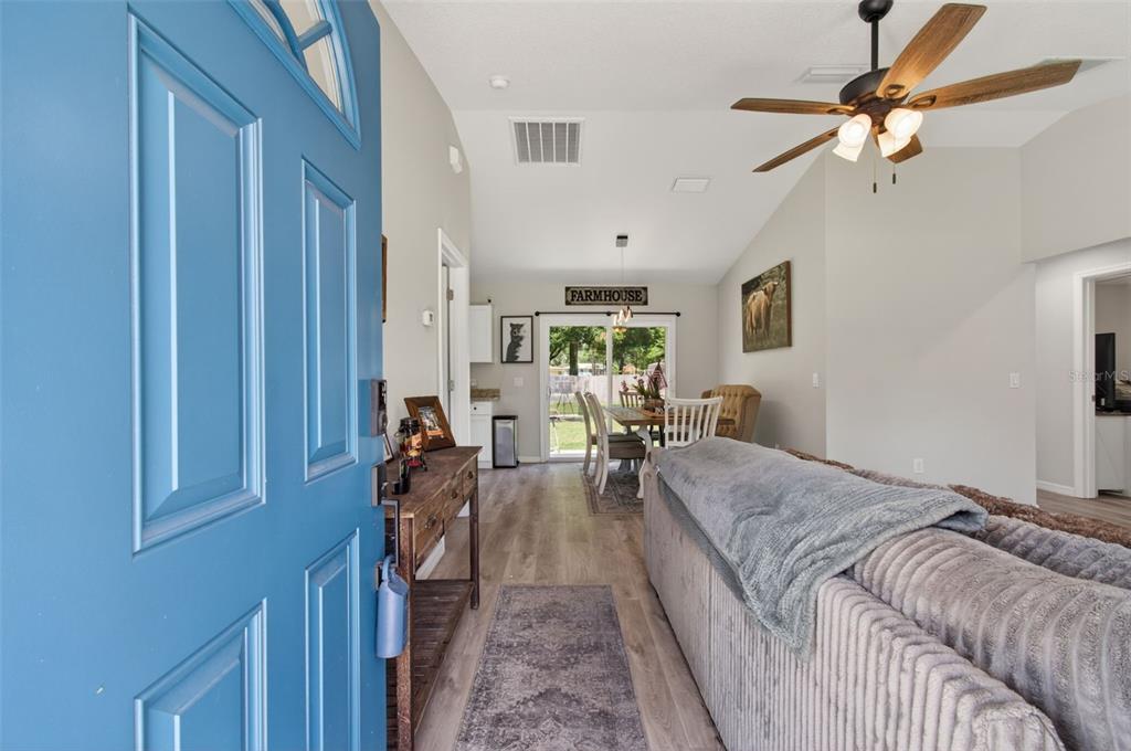 A view from a blue front door into a living room with wood-look flooring — 14027 SE 43RD TERRACE, SUMMERFIELD, FL