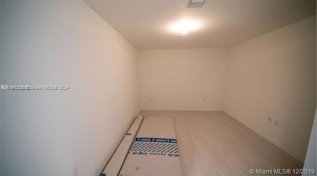 An empty room features light-colored wood-look flooring, white walls, and a central ceiling light — 1000 Brickell Plz # 4905, Miami FL 33131, MIAMI, FL