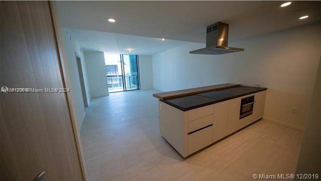 A modern kitchen island with a dark countertop sits in an open-plan living space — 1000 Brickell Plz # 4905, Miami FL 33131, MIAMI, FL